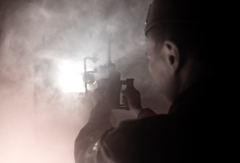Kuvassa sotilas ja konekivääri savuisessa bunkkerissa.