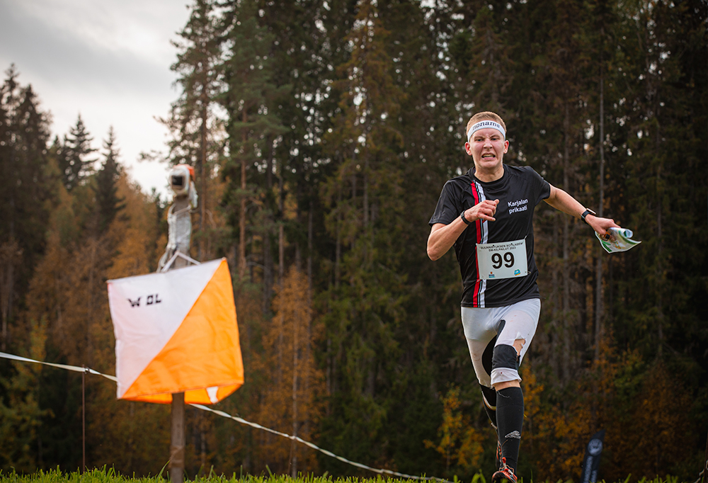 Kuvassa on Karjalan prikaatia edustava varusmies jouksemassa kohti suunnistusrada maalia urheiluvaatteissa.