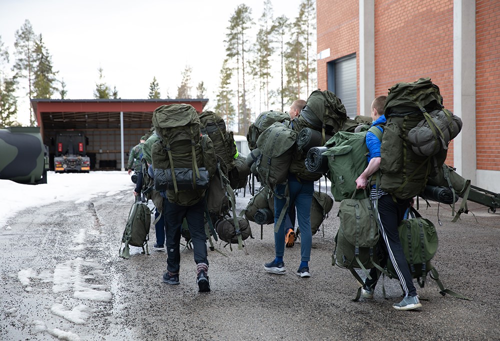 Varusmiehet kantavat varustesäkkejä.