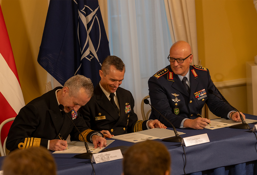 Nato-komentajat hymyilevät allekirjoittaessaan asiakirjoja.