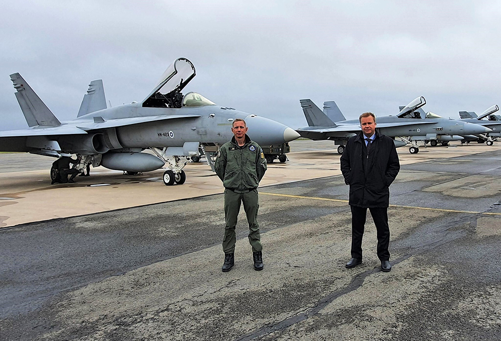 Kuvassa puolustusministeri Kaikkonen takanaan Hornet-hävittäjiä.