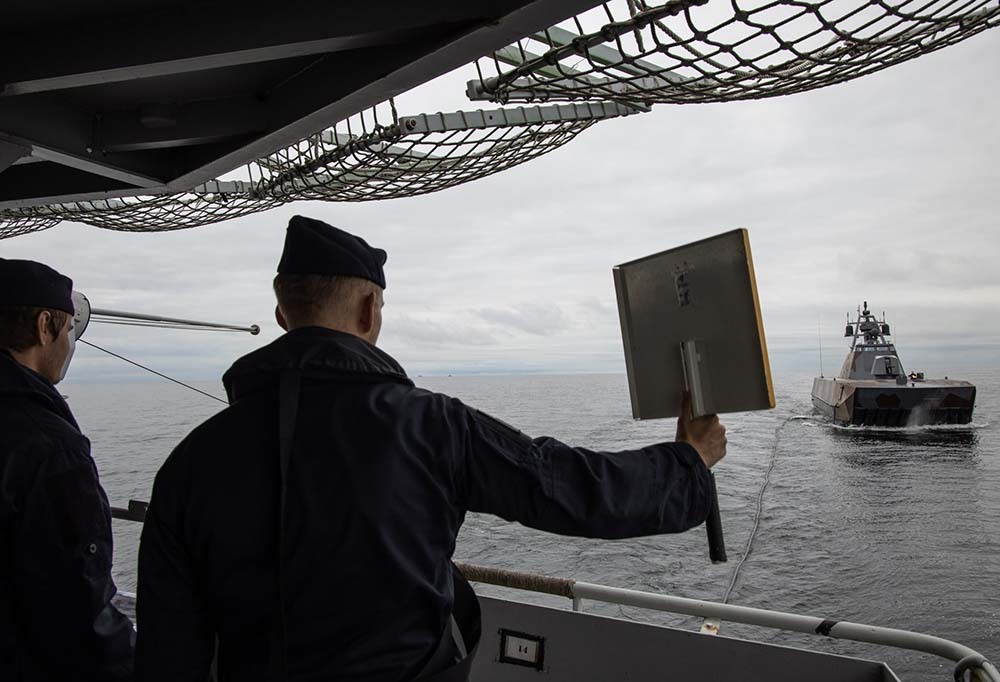 Kaksi sotilasta laivassa ohjaamassa toista alusta.