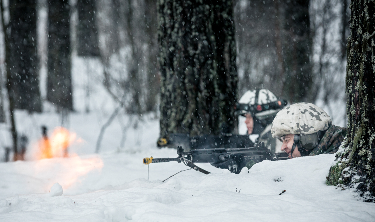Kuvassa varusmies sotaharjoituksessa tähtäilemässä aseen kanssa.