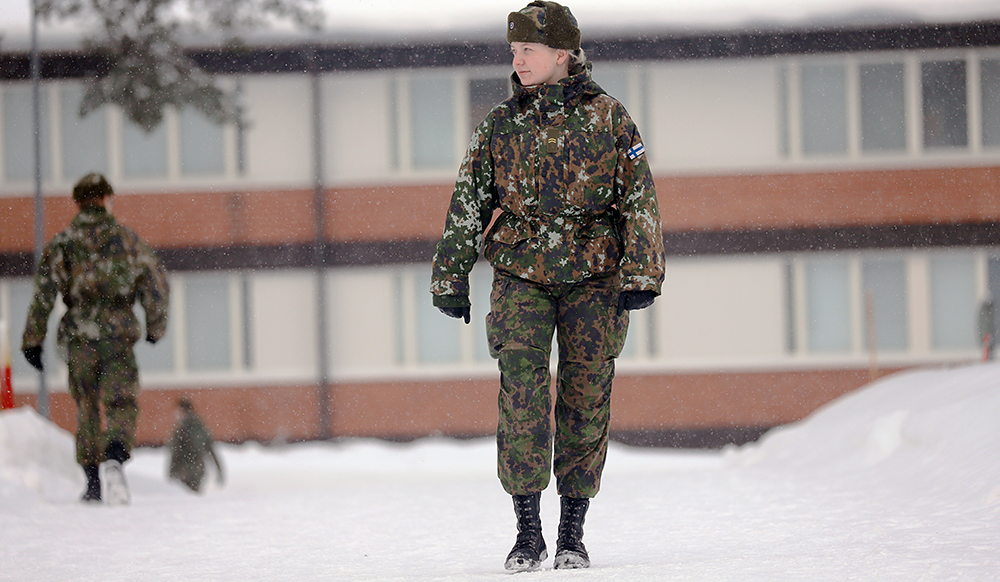 Nainen maastopuvussa kävelee ulkona talvimaisemassa.