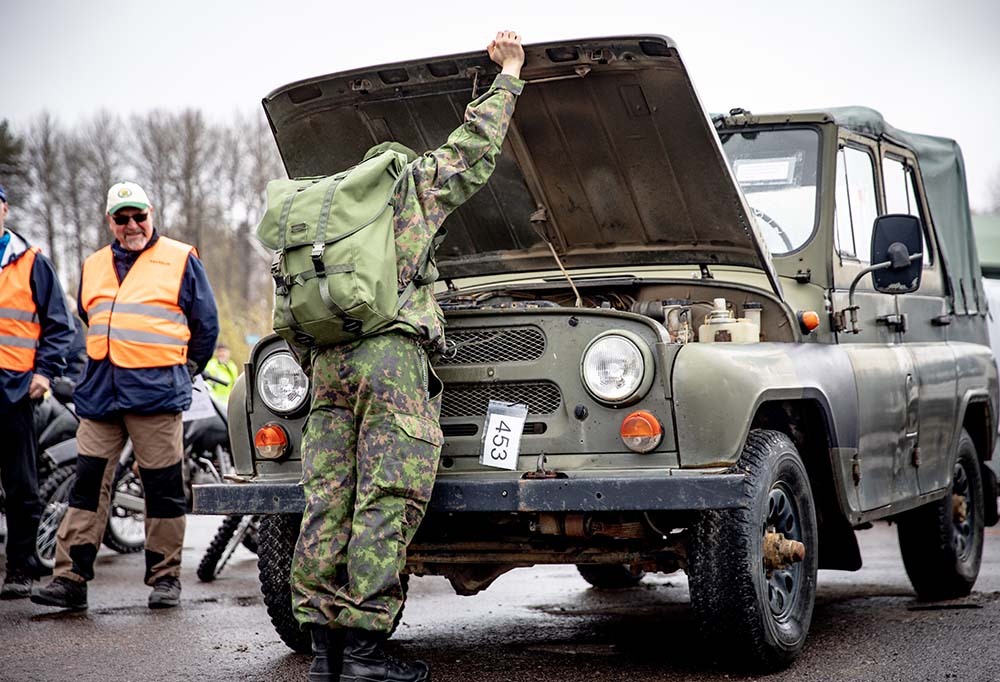 Varusmies katsoo vanhan Puolustusvoimien auton konepellin alle.