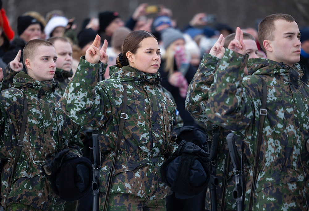 Alokkaat vannomassa sotilasvalaa pakkastakit päällään. Taustalla yleisöä.