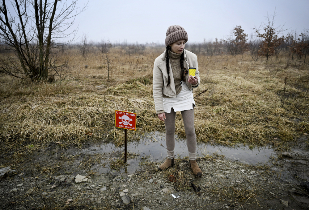 Ukrainalainen nainen seisomassa Ukrainassa miinoitetulla pellolla