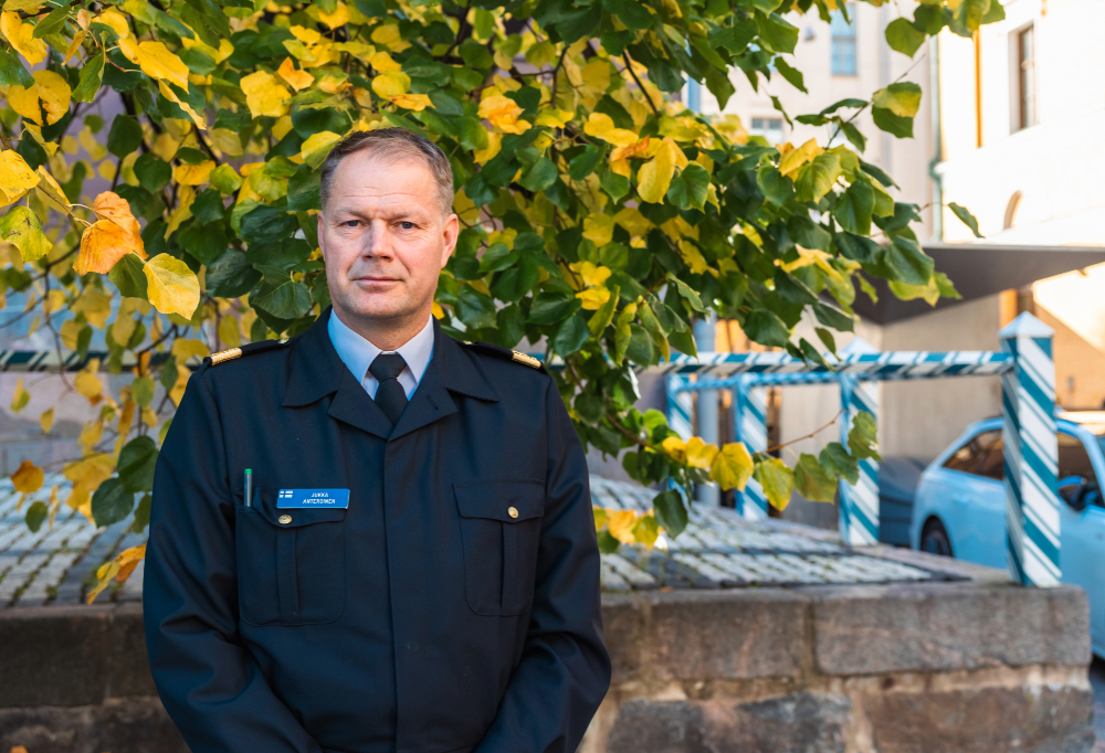 Jukka Anteroinen seisoo ja katsoo kameraan puun edessä, kaupunkiympäristössä.