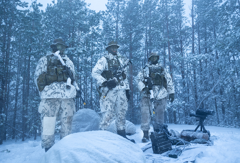 Kolme meritiedustelijaa talvisessa kelissä. Taustalla luminen metsä.