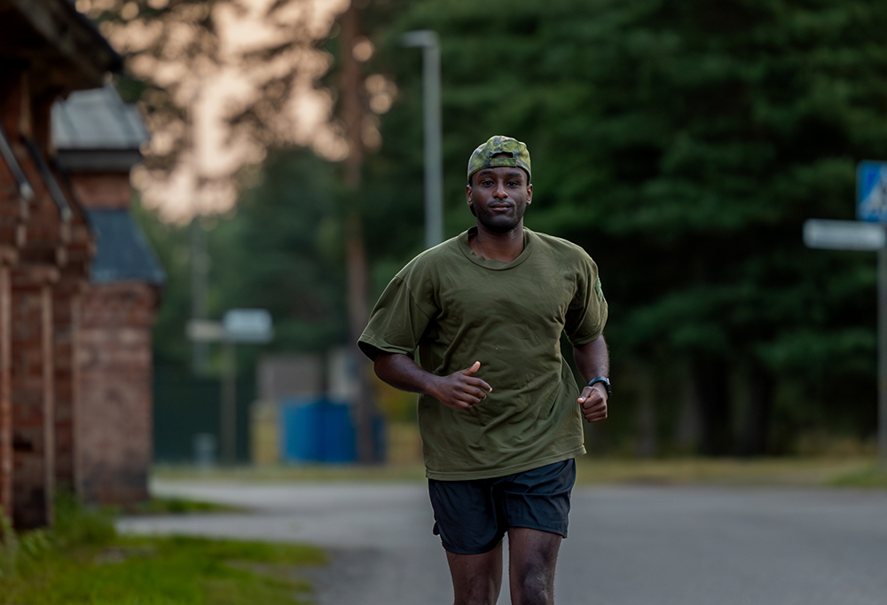Varusmies juoksee tiellä liikuntavarustuksessa.