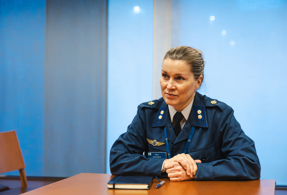 Eversti Inka Niskanen istuu pöydän ääressä.