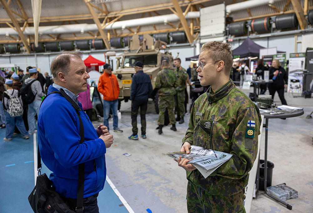 Kuvassa varusmies keskustelee messuvierailijan kanssa kokonaisturvallisuusmessuilla.