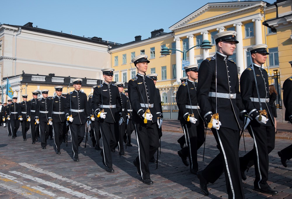 Kuvassa joukko kadettikoululaisia kävelee jonossa miekat kädessä.