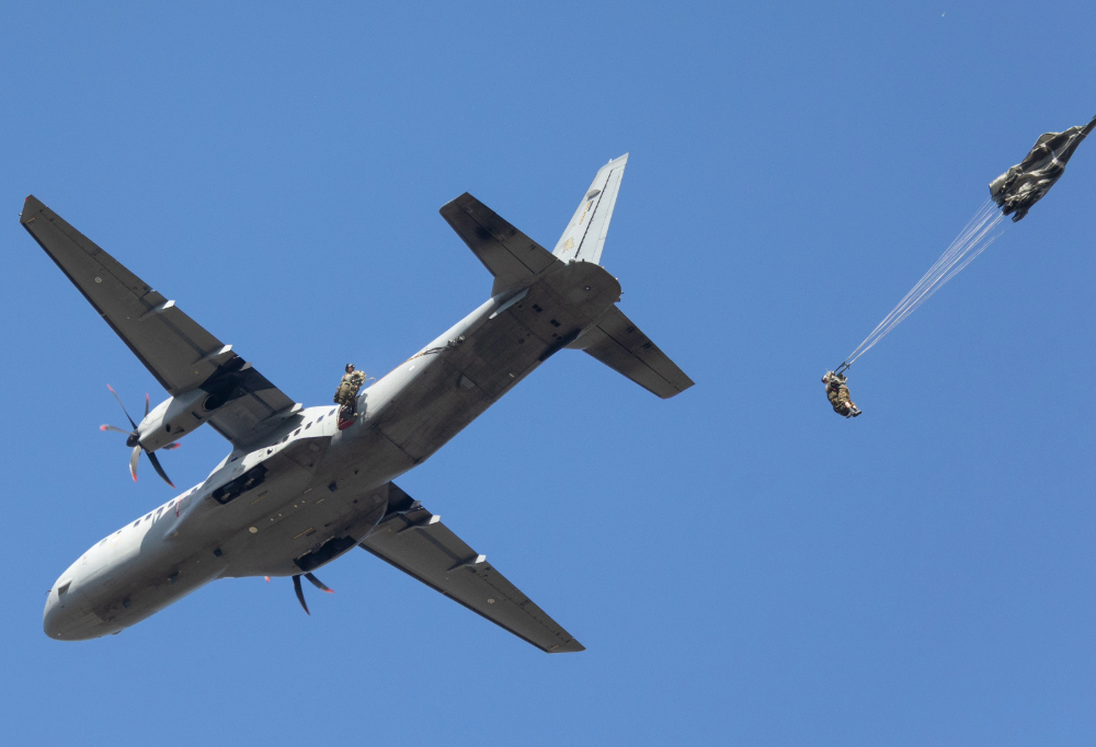Laskuvarjojääkärit hyppäävät yksi kerrallaan lentokoneesta.