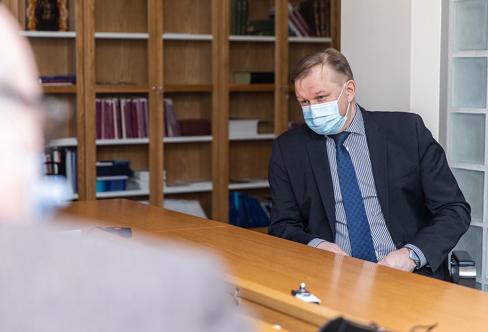 Lehtisalo istuu pöydän ääressä haastateltavana kasvomaski päässä.