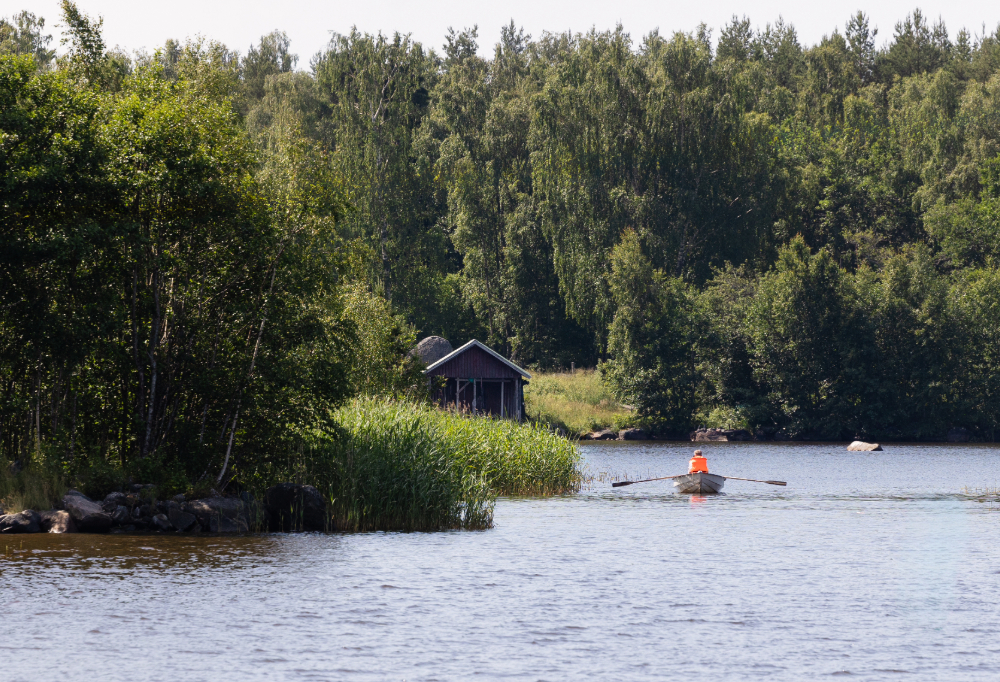 Maisemakuvassa näkyy henkilö soutamassa soutuveneellä.