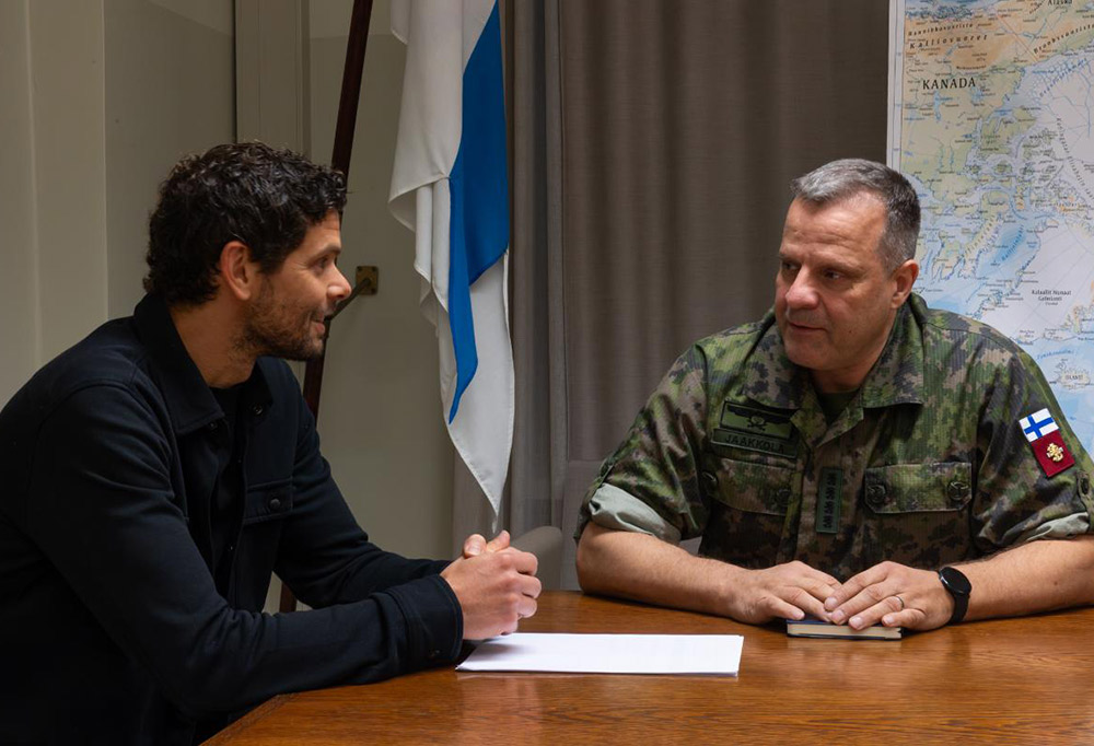 Janne Jaakkola ja Peter Sarlin keskustelevat pöydän ääressä. Taustalla Suomen lippu ja kartta.