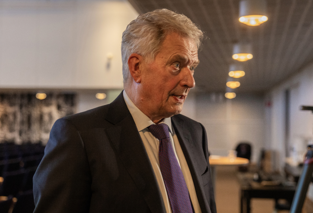 Presidentti Niinistö lähikuvassa. Hän katsoo oikeaan laitaan. Taustalla auditorio, jossa paljon tuoleja.