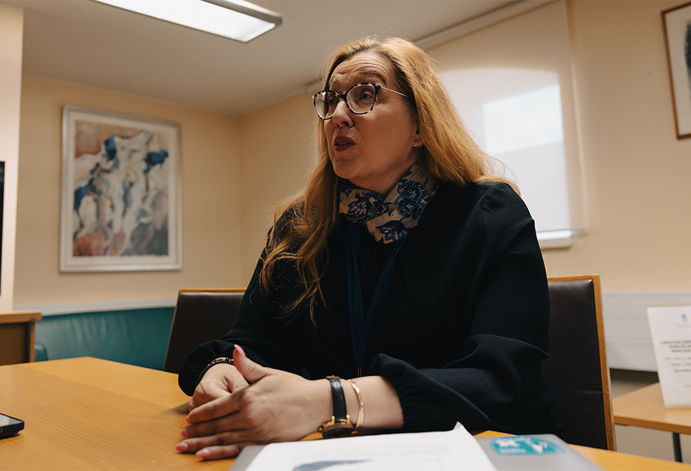 Kristiina Olsson istuu pöydän ääressä.