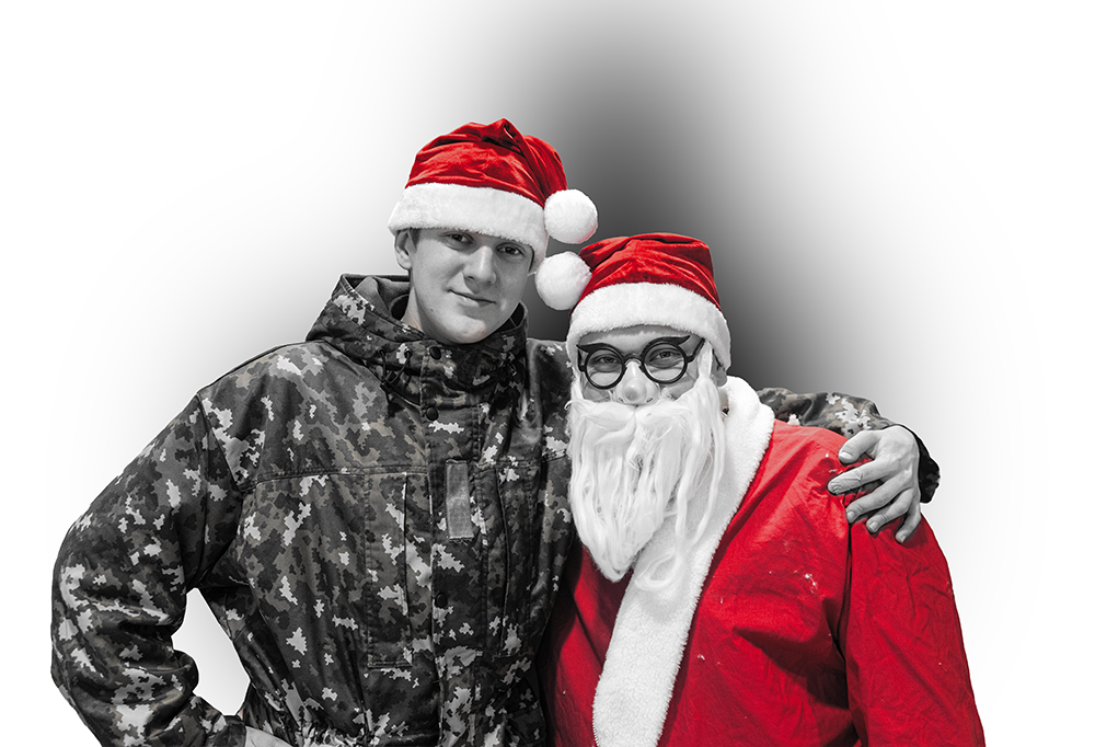 Tonttulakkiin pukeutunut kaartinjääkäri Matias Merrifield pitää kättään joulupukin olkapäällä.