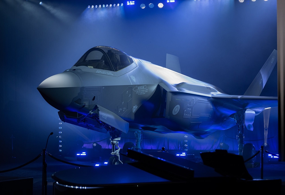 F-35 -hävittäjä esiintyy lavalla sinisten valojen alla.