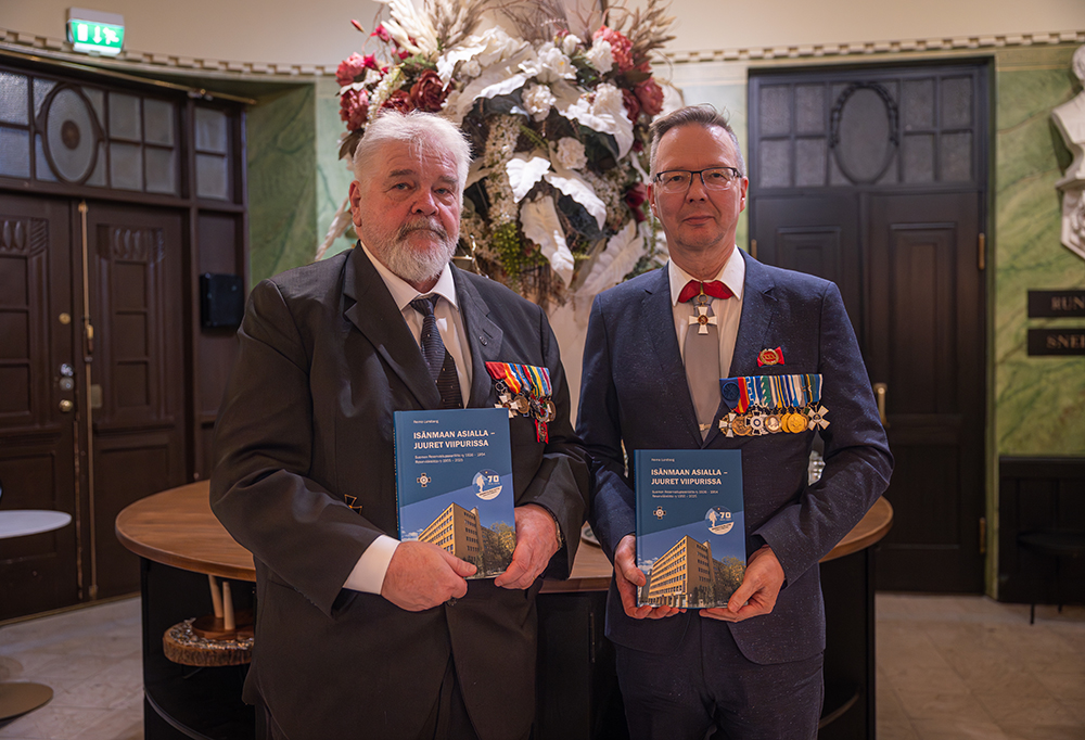 Lundberg ja Mustaniemi seisovat, pitävät uutuuskirjoja käsissään ja katsovat kameraa.