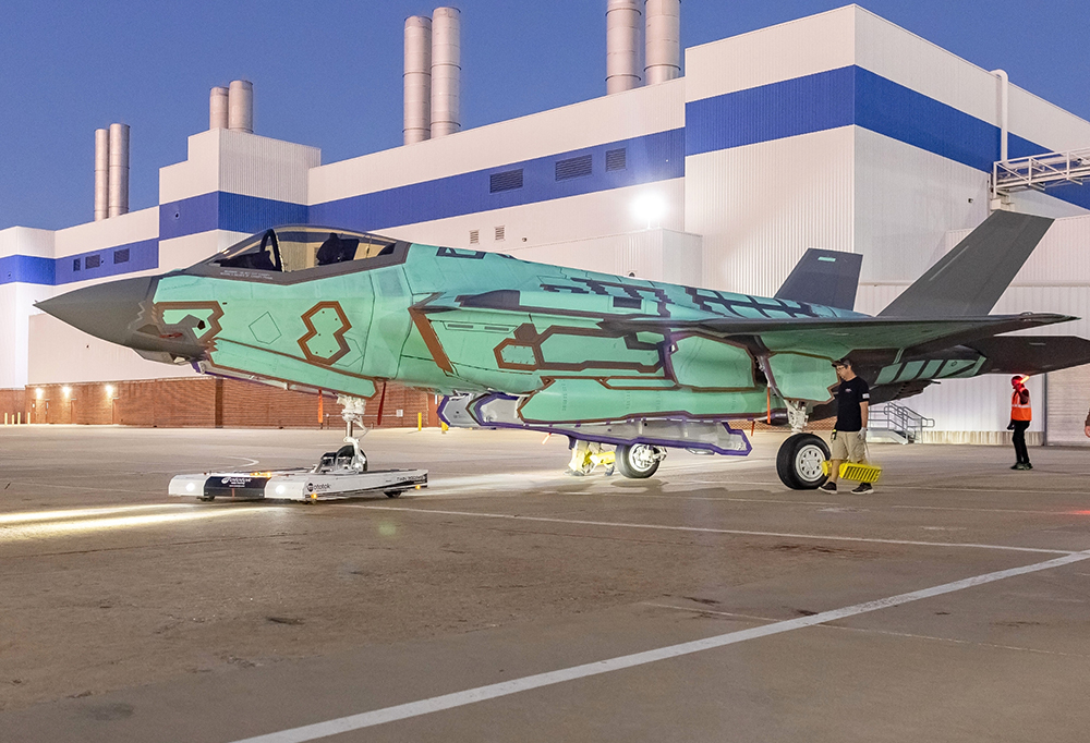 Turkoosiksi maalattu F-35-hävittäjä pysäköitynä asvalttikentälle.