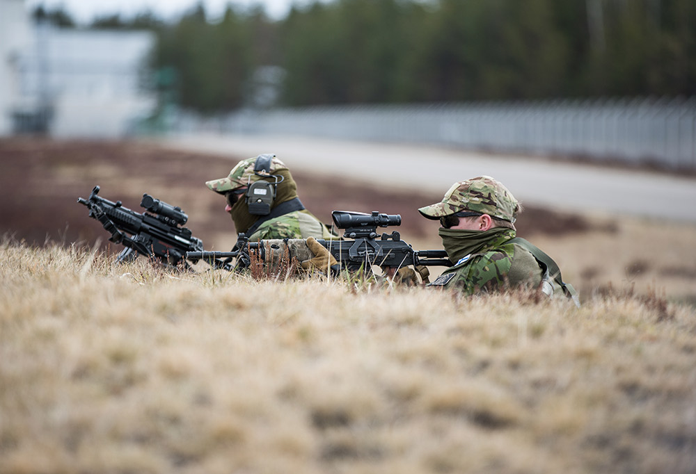 Kaksi taistelijaa piiloutuneena kivääriensä kanssa vallin taakse.