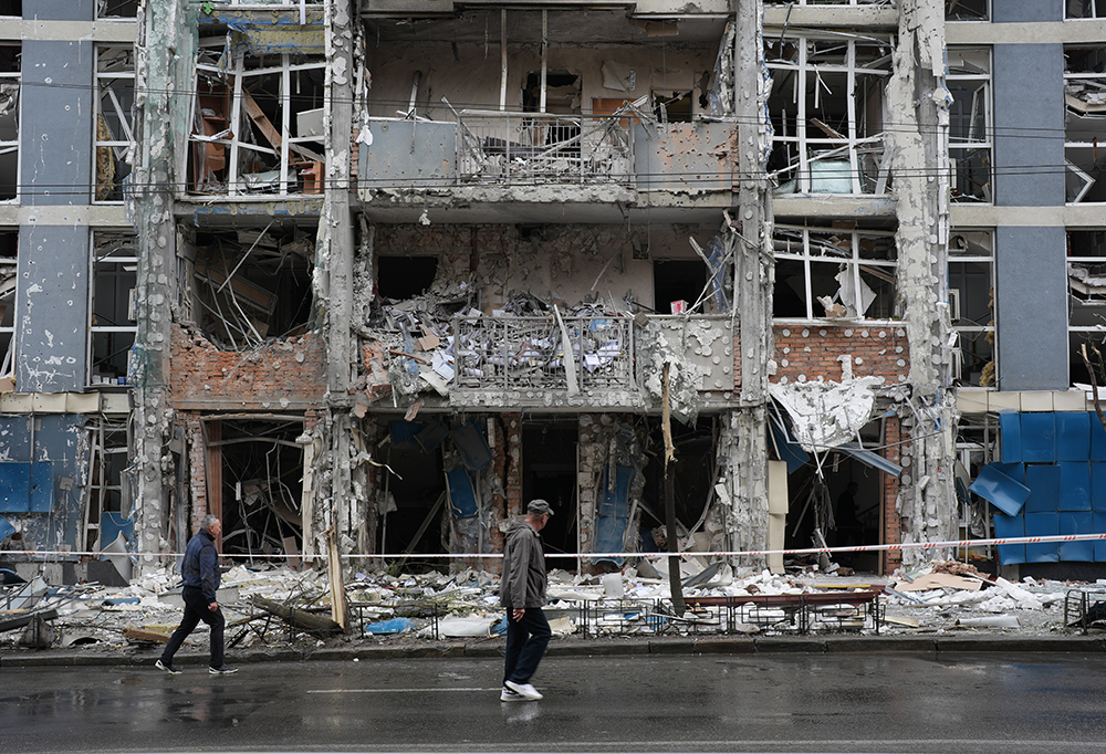 Ukrainalainen kerrostalo, jonka edusta on tuhottu. Edessä olevalla tiellä kävelee kaksi miestä.