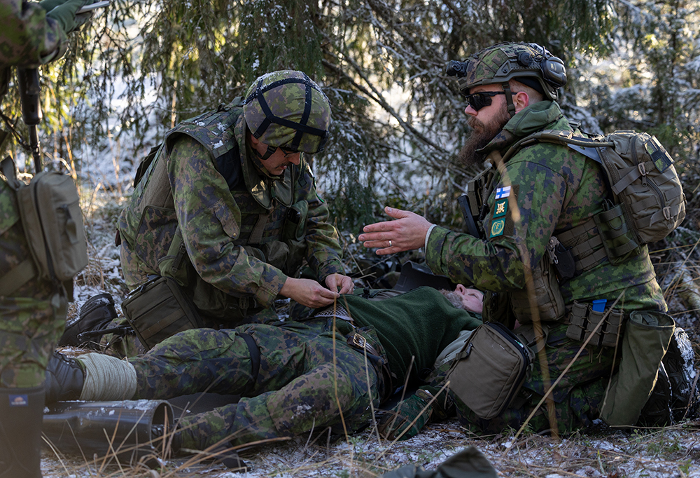 Kaksi taistelijaa antaa taisteluensiapua haavoittuneelle.