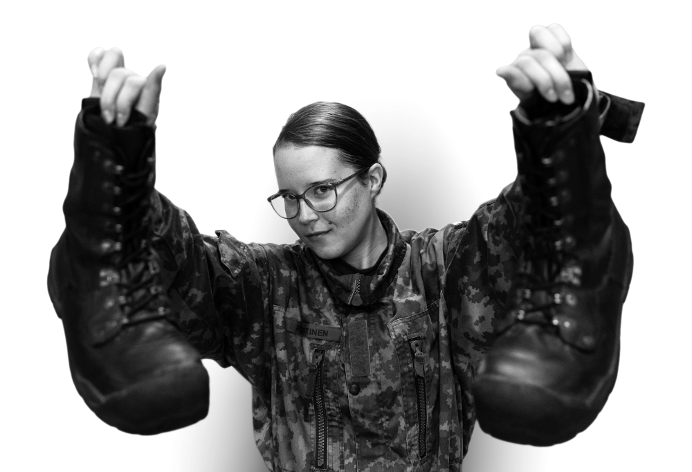 Kaartinjääkäri Annika Puustinen seisoo maihinnousukengät käsissään.