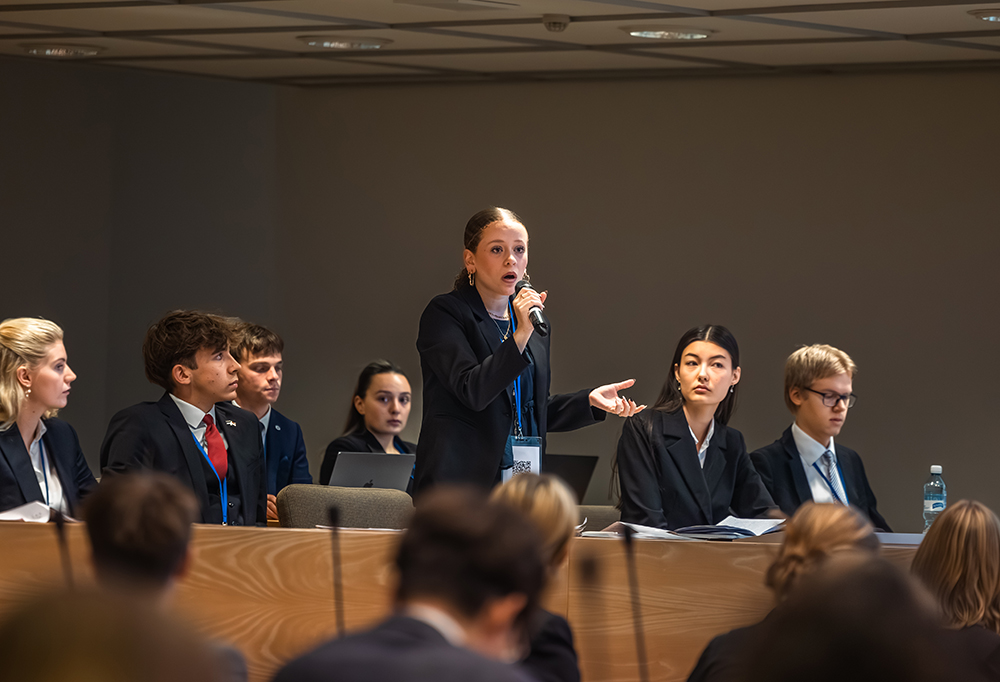 Nuoret edustajat istuvat istuntosalissa. Keskellä oleva Robin Sofie Bulo puhuu mikrofoniin.