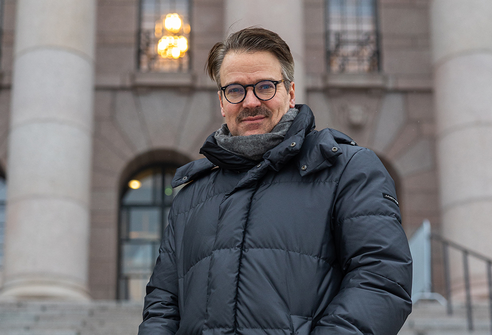 Niinistö seisoo talvitakissaan harmaatiilisen Eduskuntatalon edessä