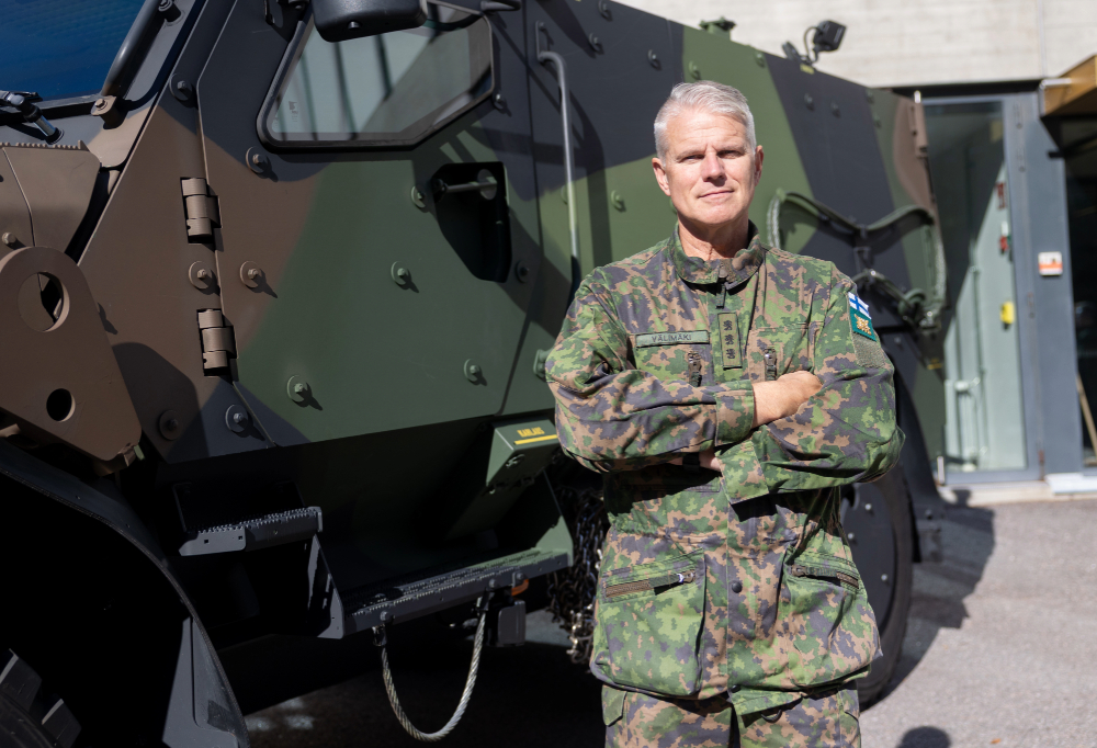 Maavoimien komentaja seisoo miehistönkuljetusvaunun edessä.