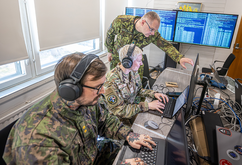 Kuvassa reserviläiset maastopuvussa näpyttelevät tietokonetta.