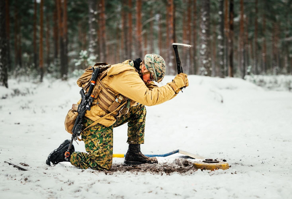 Kuvassa sotilas kaivaa maata kenttälapiolla.