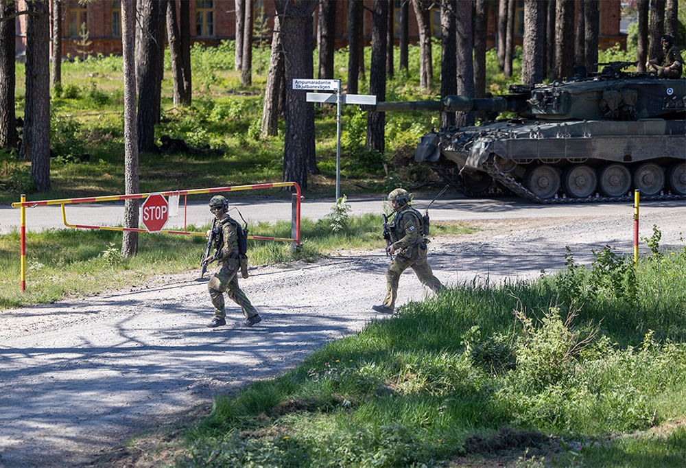 Leopard -taistelupanssarivaunu ja varusmiehet etenevät soratiellä.