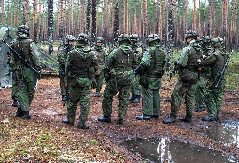 Joukko asevelvollisia seisomassa metsässä.