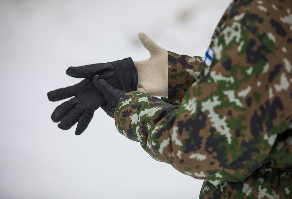 Kuvassa varusmies laittamassa tuplahanskoja käteensä.