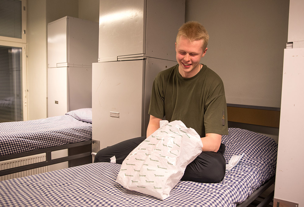 Kuvassa varusmies saa iloisena sotkupussin eristystupaansa.