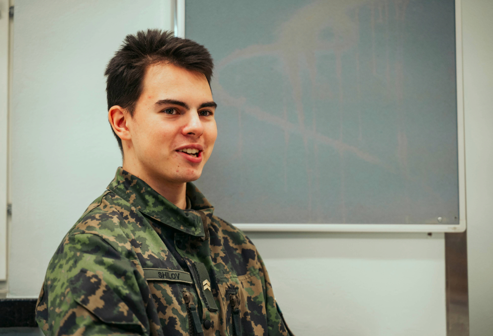 Sopimussotilas hymyilee ja katsoo vinosti kameraan.