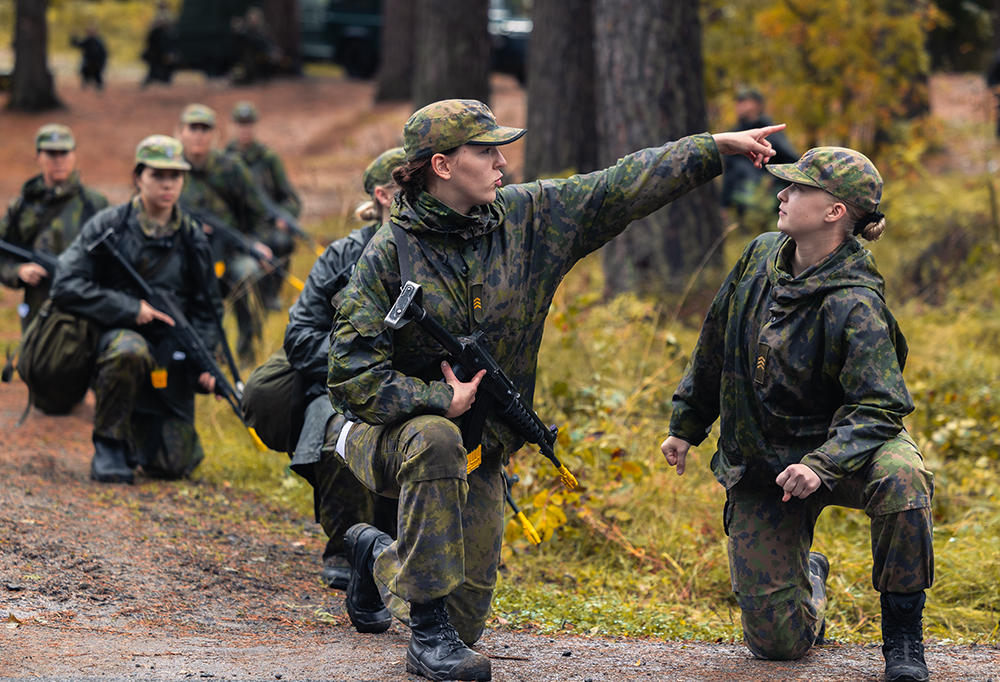 Kurssin johtajat ja kurssilaisia korkeassa polviasennossa metsässä aseiden kanssa.