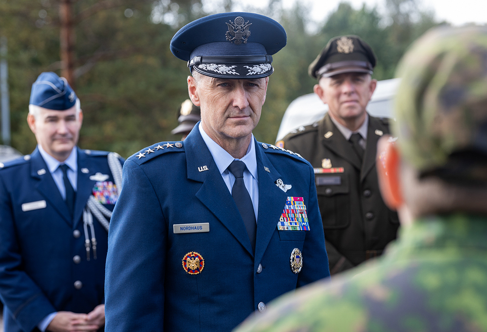 Kenraali Nordhaus. Takana upseereita ja metsää. Etualalla suomalaisen sotilaan takaprofiili.