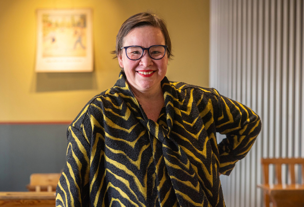 Rosa Meriläinen katsoo kameraa ja hymyilee.