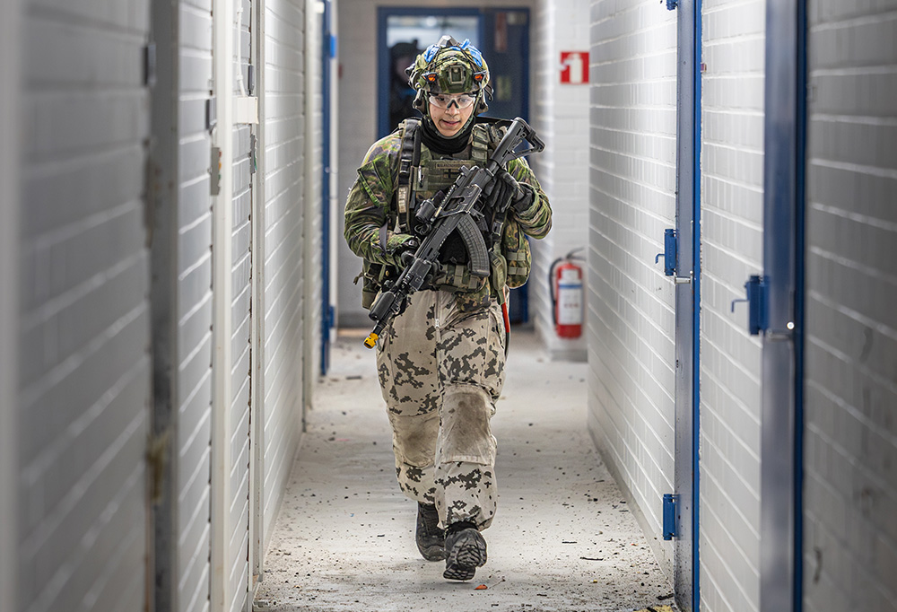 Kuvassa valmiusyksikön taistelija juoksee käytävällä taisteluvarustuksessa.