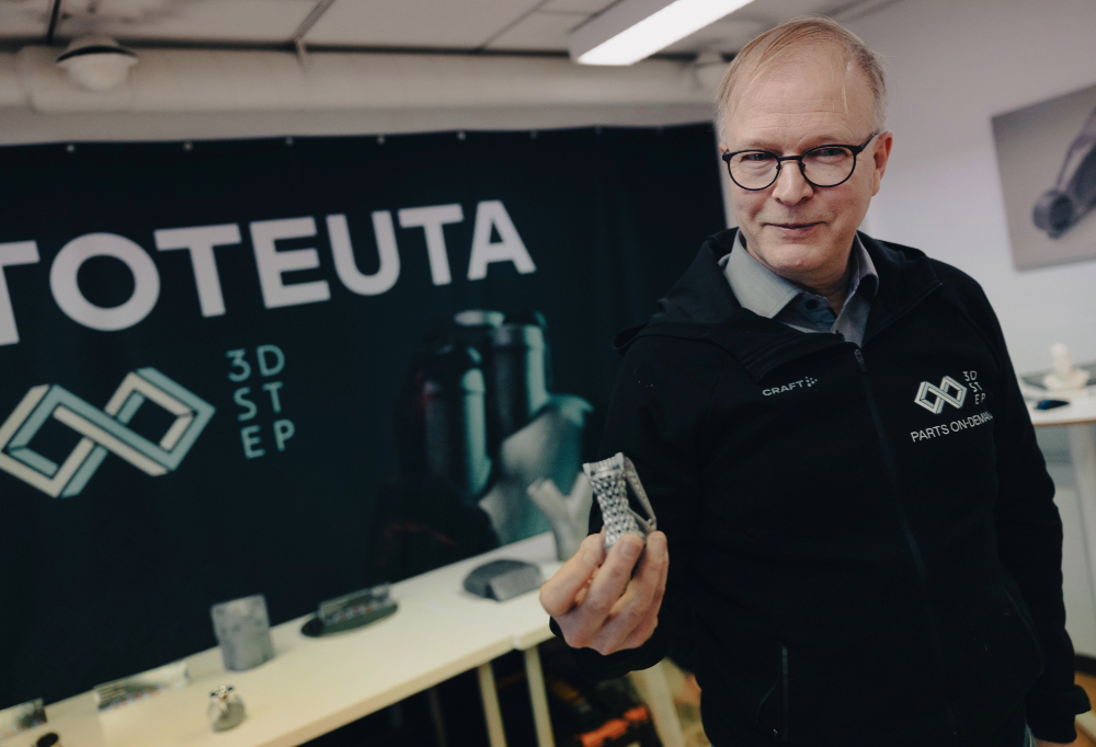 Pekka Ketola pitää 3D-tulostettua osaa kädessään.