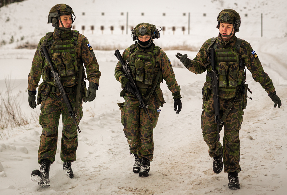 Kolme valmennettavaa sotilasta kävelee talvisella ampumaradalla.