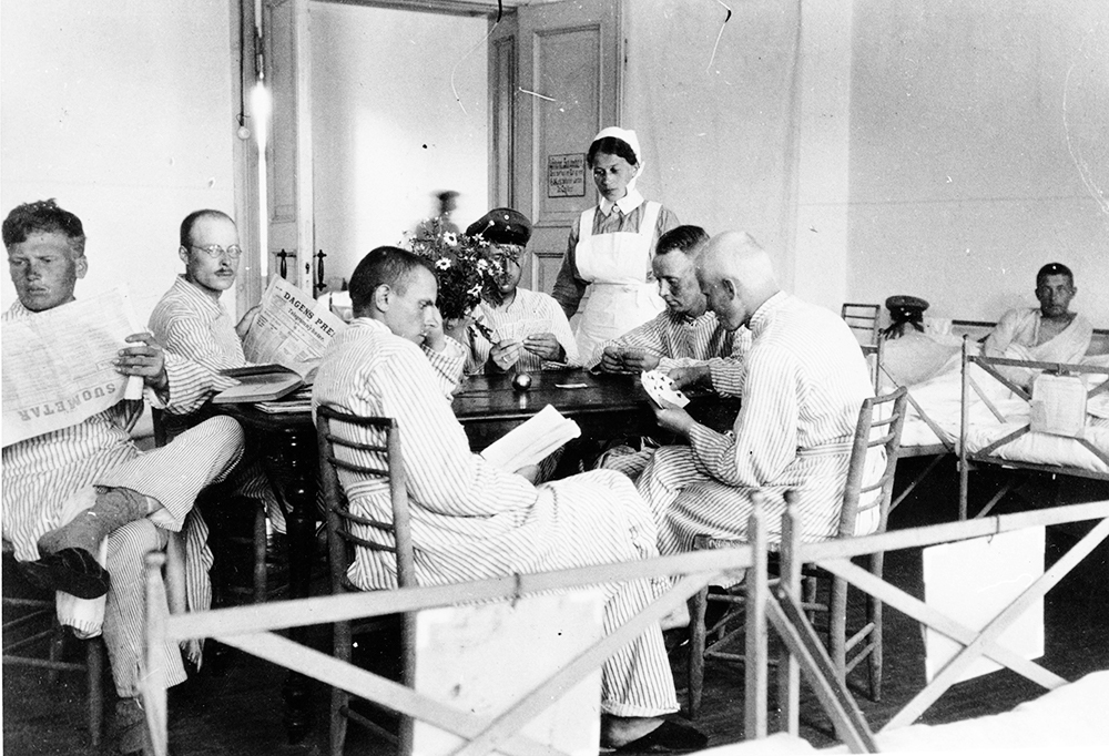 Kuvassa jääkärien sairaanhoitaja Saara Rampanen Liepajassa yhdessä potilaidensa kanssa.