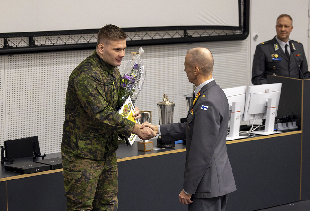 Kersantti kättelemässä kenraaliluutnanttia auditorion edessä.