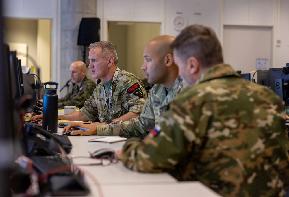 Neljä taistelijaa työskentelee tietokoneella pöydän ääressä.